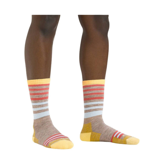 Pair of knee-high striped socks in tan, cream, yellow, red, and gray on model legs