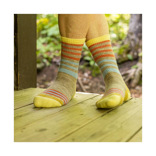 Pair of knee-high striped socks in yellow, orange, blue, and tan on a wooden deck