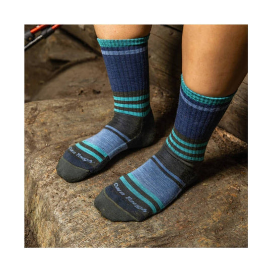 Blue and teal striped hiking socks worn on feet standing on a rock