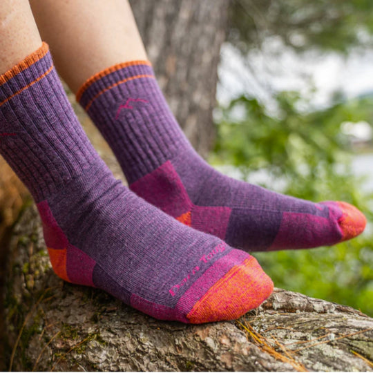 Purple and magenta hiking socks with orange trim worn on feet outdoors.