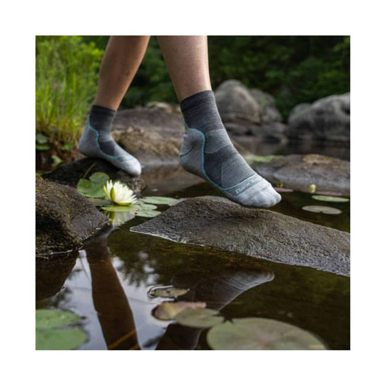 Gray and dark navy ankle hiking socks with light blue trim, shown on feet stepping across rocks by water