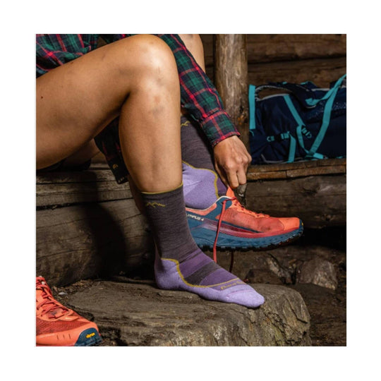 Purple hiking sock on a seated model's foot, shown with a trail shoe