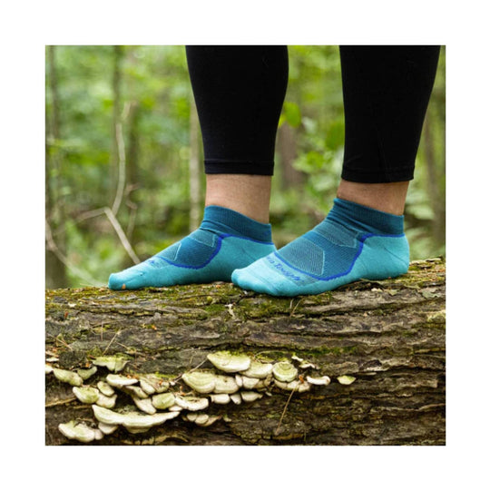 Light blue no-show ankle socks with darker blue accents worn outdoors on a log
