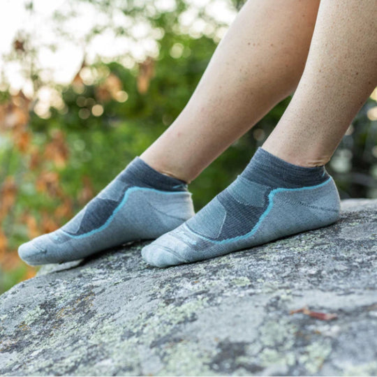 Gray no-show athletic socks with blue trim worn on feet outdoors on a rock