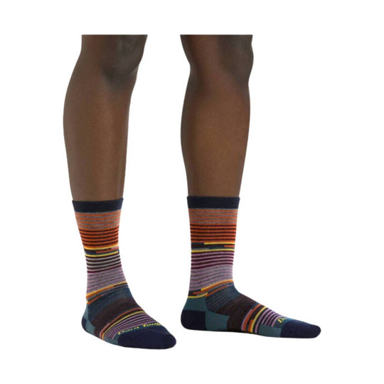 Pair of patterned crew socks on a model’s lower legs, with multicolor stripes and navy toes and heels