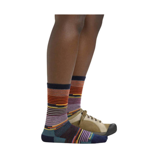 Multicolored striped crew socks on a model wearing beige lace-up shoes