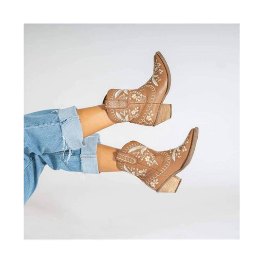 Brown embroidered cowboy boots worn with cuffed light blue jeans
