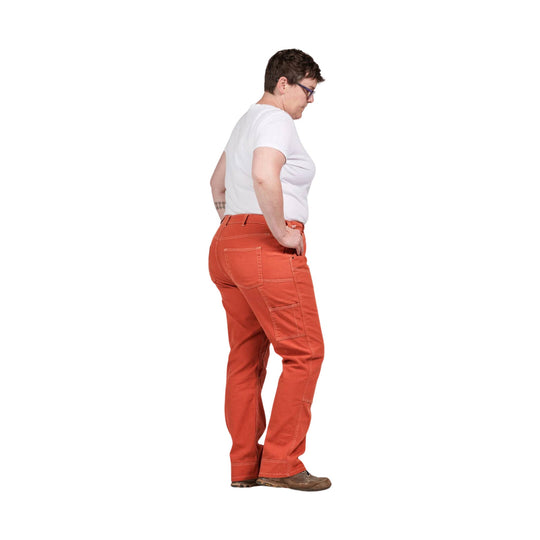 Side-view of a woman wearing bright orange work pants, a white T-shirt, and brown shoes