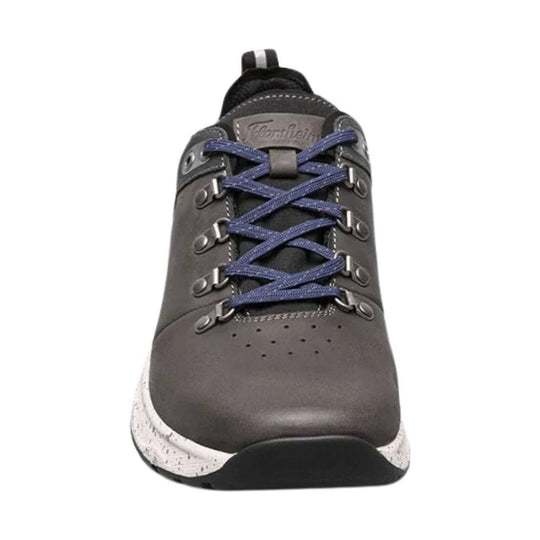Grey low-top sneaker with blue laces, metal eyelets, and a speckled white midsole