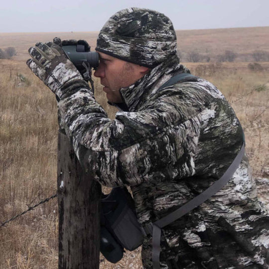 Camouflage fleece beanie worn outdoors by a person using binoculars