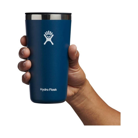 Blue insulated tumbler with metal rim and white Hydro Flask logo, held in one hand