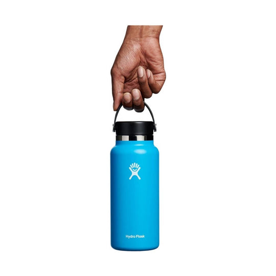 Blue wide-mouth water bottle with a black lid and carry handle, shown held by a hand