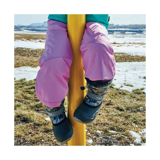 Toddler winter boots hanging from a yellow pole in snow
