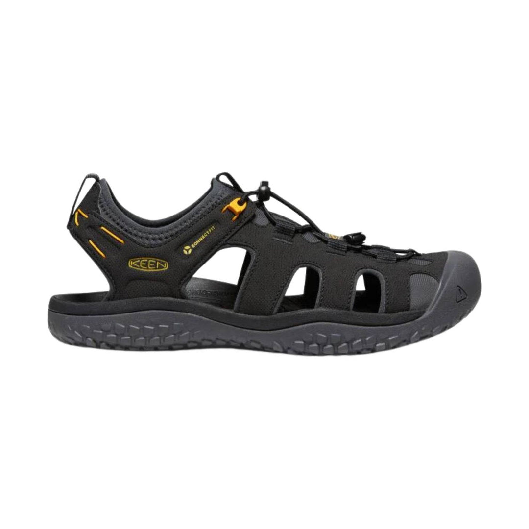 Black closed-toe hiking sandal with yellow accents, bungee laces, and side cutouts