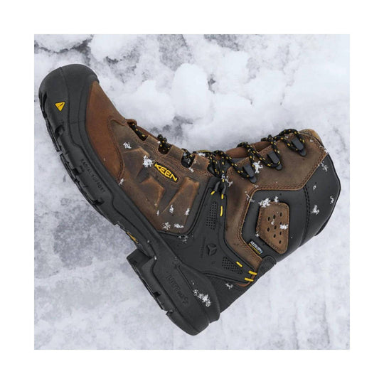 Brown and black insulated lace-up work boot with yellow accents, shown on snow