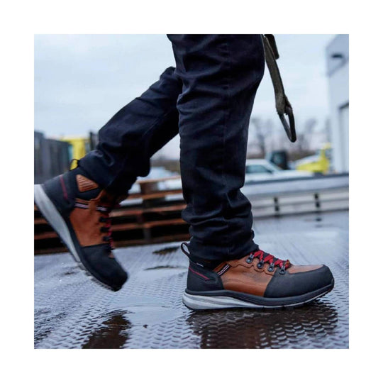 Mid-height work boots in brown and black with red laces, shown on a wet surface