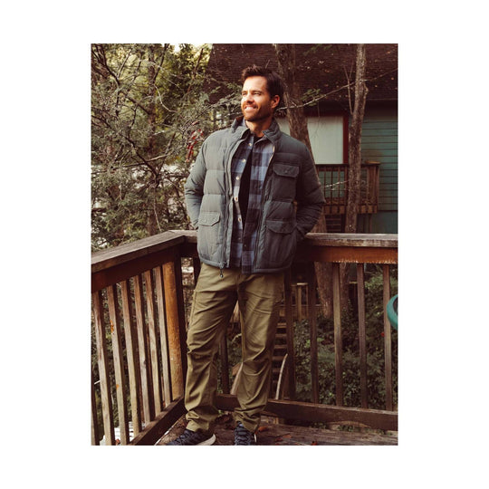 Gray quilted hoodless puffer jacket worn over a plaid shirt, shown with khaki pants and hiking shoes