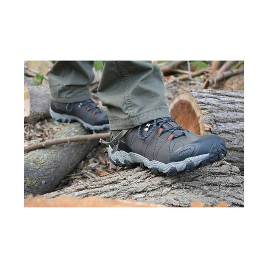 Gray and black mid-cut hiking boot with rugged tread and bungee laces, shown on a log