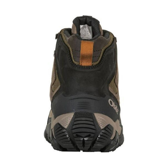 Black and tan mid hiking boot viewed from the back with rugged tread and an orange pull tab.