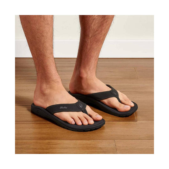 Black thong-style flip-flop sandals on a person's feet