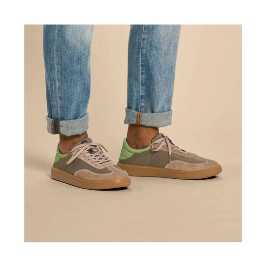 Gray and tan low-top sneakers with light laces, green heel accents, and gum soles