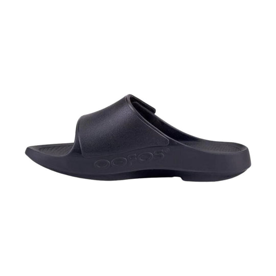 Black foam slide sandal with a wide strap and embossed OOFOS logo