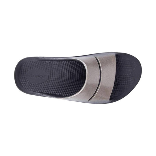Black and metallic slide sandal with a textured footbed and embossed logo on the insole