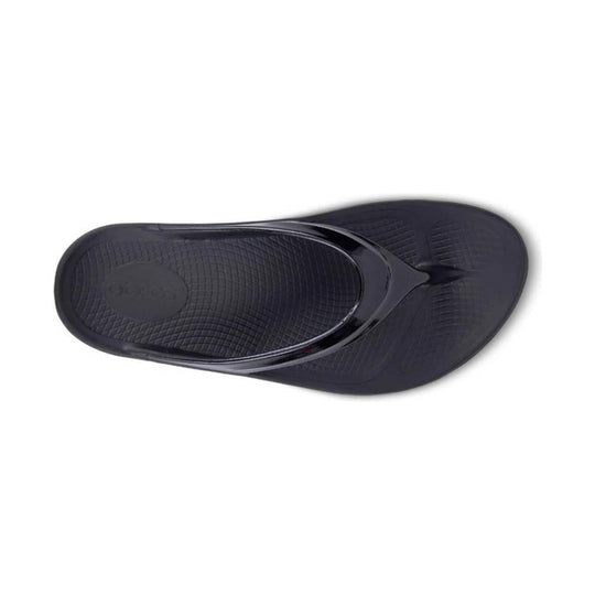 Black thong slide sandal with a textured footbed and glossy strap
