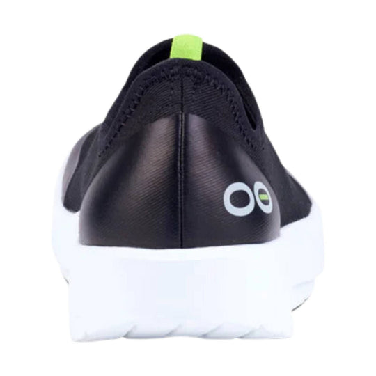 Black slip-on shoe with white sole, lime green heel tab, and small side logo