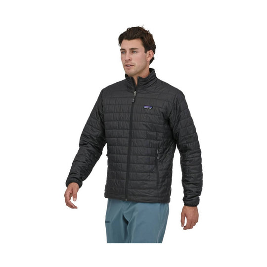 Black quilted zip-up jacket with a stand collar and chest logo patch, worn by a model