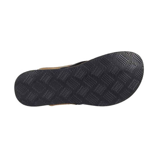 Black sandal outsole with deep zigzag tread pattern and tan upper edges peeking along the sides