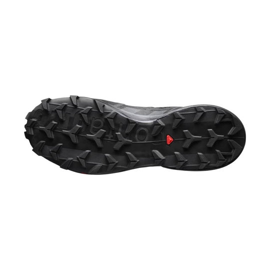 Black trail running shoe outsole with deep lugged tread and a small red accent