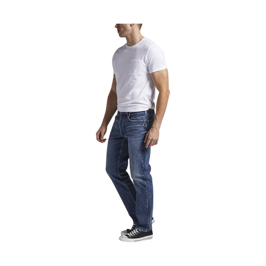 Man wearing a white crewneck T-shirt, blue jeans, and black low-top sneakers on a white background