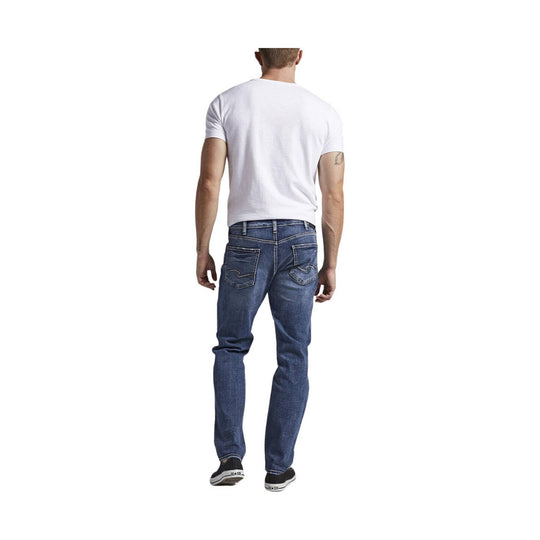 Back view of a man wearing a white T-shirt, blue jeans, and black low-top sneakers