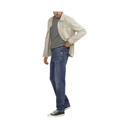 Men's straight-leg blue jeans worn with a beige overshirt, gray T-shirt, and black sneakers