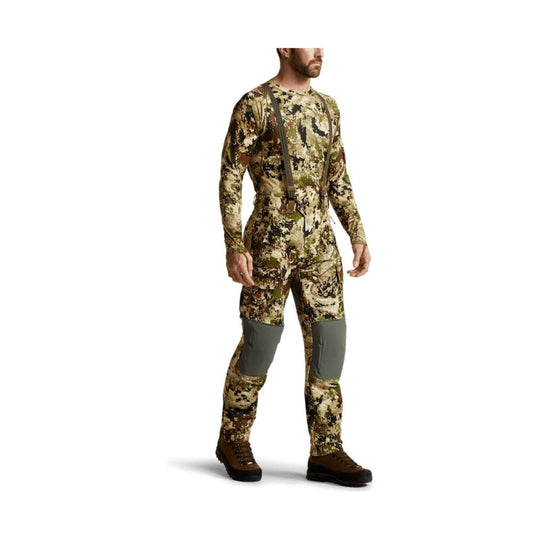 Camouflage hunting pants with gray reinforced knee panels, shown with suspenders and boots