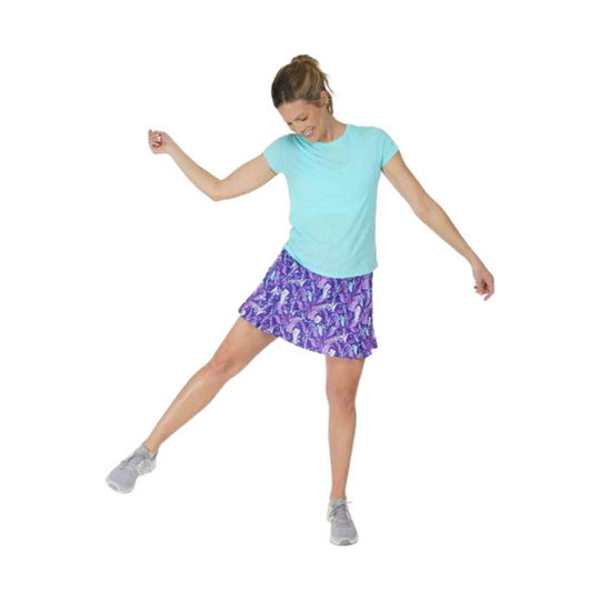 Women’s purple patterned athletic skirt with a light blue T-shirt and gray sneakers