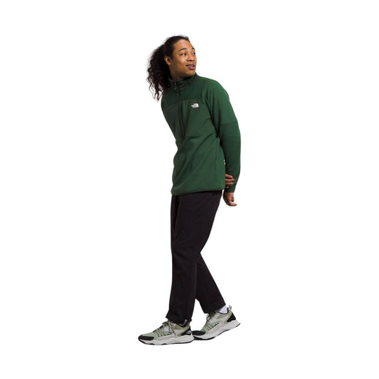 Green half-zip fleece jacket with a small chest logo, worn with black pants and sneakers