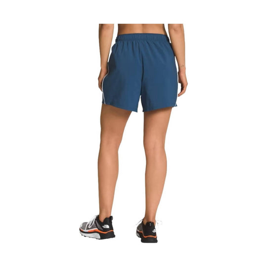 Blue athletic shorts shown from the back on a model, with an elastic waistband and white side piping.