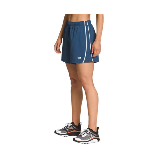 Blue women’s running shorts with white side stripes and a small logo on the leg, shown with a model wearing running shoes