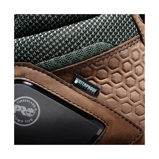 Close-up of a brown work boot with green knit collar, hex-pattern leather, and a waterproof membrane label