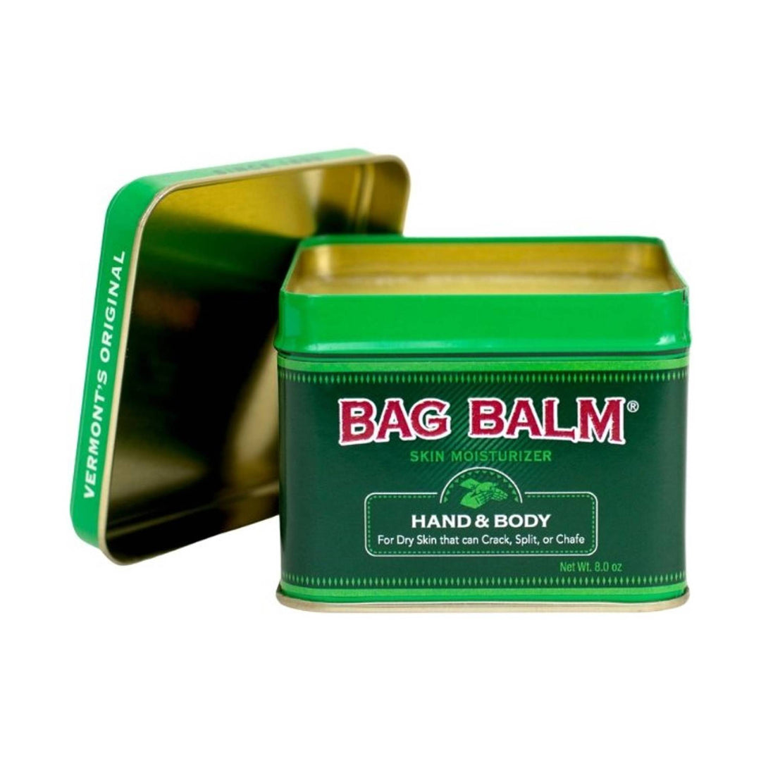 Green metal tin of hand and body skin moisturizer with lid propped behind it