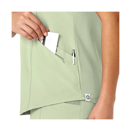 Light green V-neck scrub top with a chest pocket holding a card and pen