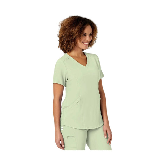 Light green V-neck scrub top with short sleeves and front pockets, worn with matching scrub pants