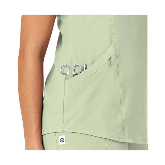 Light mint green scrub top with a curved side pocket holding scissors